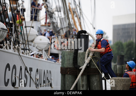 Ein Mitglied der Küstenwache aus Bereich Hampton Roads Haken eine Befestigungsleine von der Coast Guard Cutter Eagle um einen Delphin bei Landung der High Street in der Innenstadt von Portsmouth, Virginia, Freitag, 13. September 2013. Der Adler, Haus-portiert in New London, Connecticut, ist ein 295-fo Stockfoto