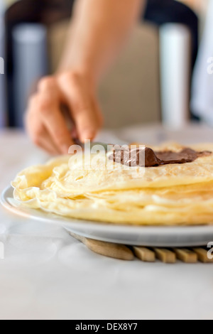 Stapel von frischen Pfannkuchen mit süßer Schokocreme auf einem weißen Teller Stockfoto