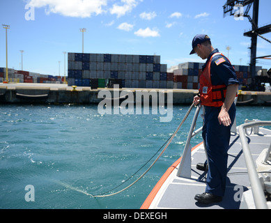 Coast Guard Petty Officer 1st Class James Moore mit der Strike Force Atlantic Strike Nationalmannschaft, kümmert sich ein Wasser Qualitätsinstrument zur Überwachung von abgereichertem Sauerstoff und pH Niveaus in den Hafen von Honolulu, Honolulu 15. September 2013. Personal von der Küste entfernt Stockfoto