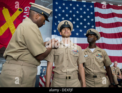 Chief Aviation Boatswain Mate (Handling) Rufus Brennnesseln, blickt links und Pins ein Anker auf Chief Aviation Boatswain's Mate (Handling) Anthony Pena während Chef Aviation Support Ausrüstung Techniker Marvin Pelzer auf in ein Chief Petty Officer Ceremon anheften Stockfoto