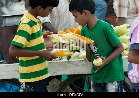 Indische jungen Kauf gekocht Maiskolben süß bei einem indischen Straßenmarkt. Indien Stockfoto