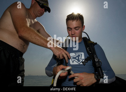 Konstruktionsmechaniker 2. Klasse James Damon hilft Navy Diver 2. Klasse Trent Gobble, beide zugewiesenen Commander Task Group (CTG) 56.1, seine Ausrüstung für eine Anti-Terror Force-Schutz-Prüfung vorbereiten. CTG 56,1 führt Sicherheit im Seeverkehr Operationen und Stockfoto