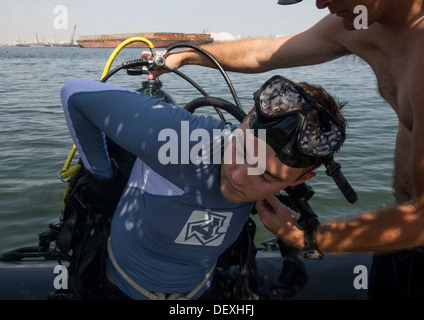 NAVAL SUPPORT Aktivität BAHRAIN (17. September 2013) Konstruktionsmechaniker 2. Klasse James Damon hilft Navy Diver 2. Klasse Trent Gobble, beide zugewiesenen Commander Task Group (CTG) 56.1, seine Ausrüstung für eine Anti-Terror Force Schutz Inspektion Tauchgang vorbereiten Stockfoto