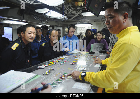 Lt. CMdR Ivan Borja, Recht, ein Flugdeck Handler an Bord des Flugzeugträgers USS George Washington (CVN-73), erklärt Flugdeck Operationen Japan Maritime Self-Defense Force Rear Admiral Yasuki Nakahata, Kommandant der Escort Flottille drei und seine staf Stockfoto