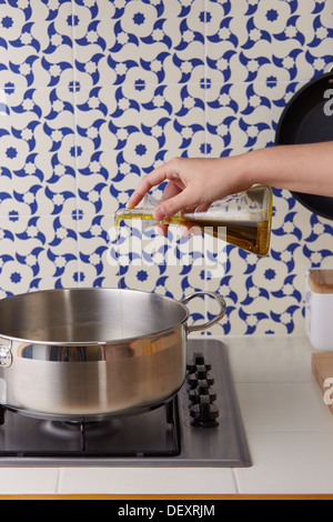 Hand gießen Öl in einer Pfanne auf einem Vintage geflieste Küche Stockfoto