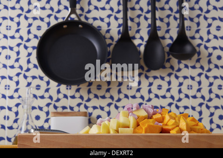 Schneiden Sie Gemüse wie Kürbis, Kartoffeln und Zwiebeln auf einem Schneidetisch in einem Vintage-geflieste Küche Stockfoto