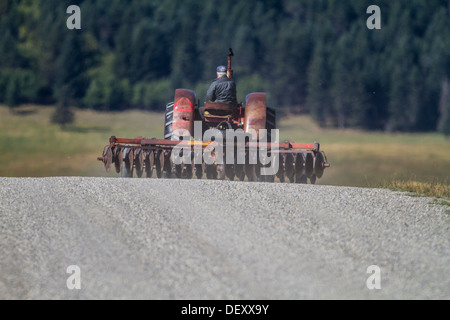 Landwirtschaftliche Szene der Landwirt Abschleppen, Maschinen, eine speziell mit einem alten Traktor auf einer ländlichen Landstraße zurück zum Gehöft Bauernhof. Stockfoto