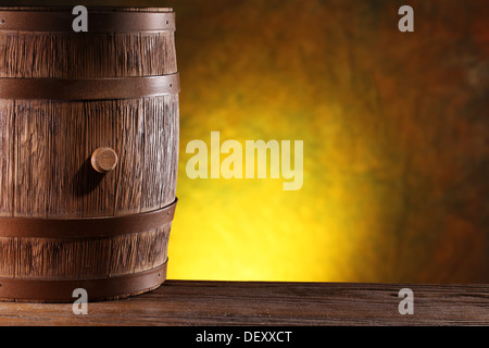 Holzfass auf einem dunklen gelben Hintergrund. Stockfoto