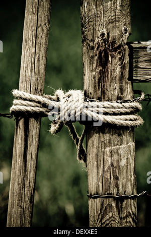 Dramatische, malerische Bild des ländlichen Holzzaun & Tor mit Seil hält es geschlossen. Was darauf hindeutet, Cowboy, Ranch, Vieh, ländlich, alt Stockfoto