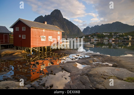 Eine typische rote Rorbuer Haus, Fischerorten an der Küste die Norwegische See in der Nähe von Reine, Bergen an der Rückseite, Insel Moskenesøy Stockfoto