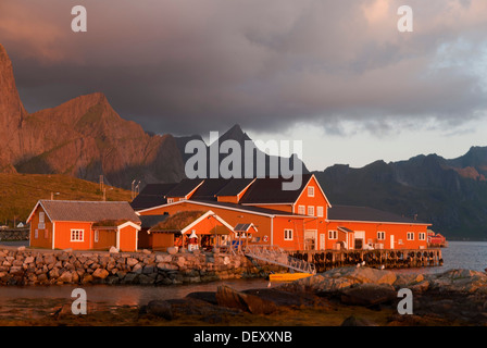 Rorbuer Hütten, Rorbu, im warmen Morgenlicht in das winzige Dorf Sakrisøy, Sakrisoy, Bergen im Hintergrund, Insel Moskenesøy Stockfoto