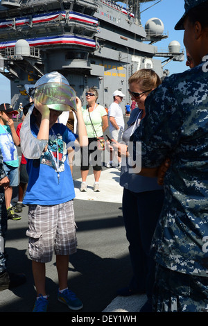 Touring der Flugzeugträger USS Ronald Reagan (CVN-76) Gast dons einen Feuerwehr-Helm während einer Demonstration vor des Schiffs Stockfoto