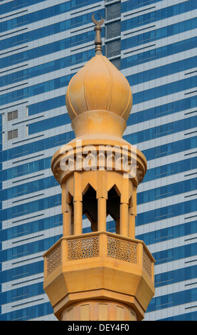 Das Minarett einer kleinen Moschee gegen die modernen Glas und Stahl Fassade eines Hochhauses, Abu Dhabi, Vereinigte Arabische Emirate Stockfoto