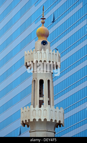 Das Minarett einer kleinen Moschee gegen die modernen Glas und Stahl Fassade eines Hochhauses, Abu Dhabi, Vereinigte Arabische Emirate Stockfoto