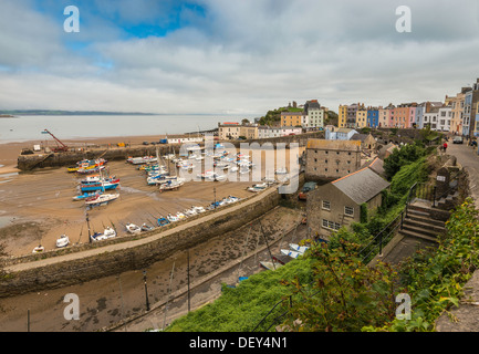 TENBY HAFEN BEI EBBE MIT FESTGEMACHTEN BOOTE UND CASTLE HILL. REGENCY REIHENHÄUSER IN PASTELLTÖNEN GEHALTEN. Stockfoto