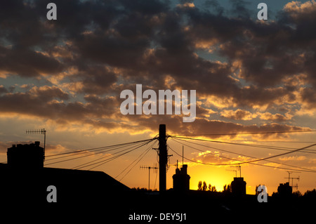 Telefonleitungen und Häuser bei Sonnenuntergang, UK Stockfoto