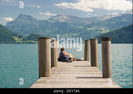 Frau sitzt auf einem Pier Wandern Stiefel stand neben ihr, am See Promenade, Weggis, Vierwaldstättersee, Kanton Luzern Stockfoto