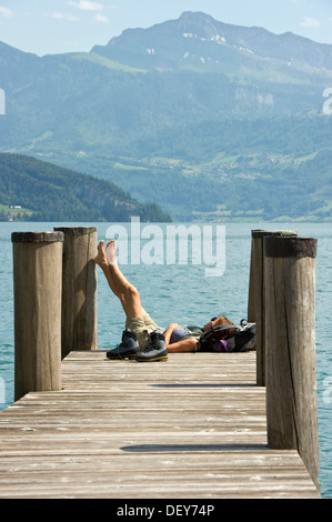 Frau sitzt auf einem Pier Wandern Stiefel stand neben ihr, am See Promenade, Weggis, Vierwaldstättersee, Kanton Luzern Stockfoto