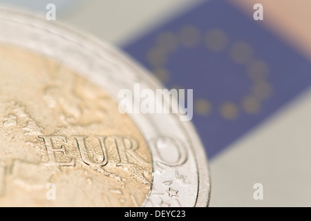 Euro-Krise, eine 2-Euro-Münze und die europäische Flagge auf einer 50 Euro-Banknote auf Rückseite Stockfoto