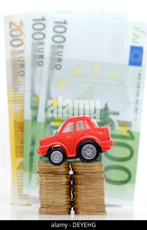 Miniatur-Auto auf einen Stapel von Münzen, Maut symbolisches Bild für Auto Stockfoto