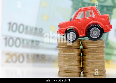 Miniatur-Auto auf einen Stapel von Münzen, Maut symbolisches Bild für Auto Stockfoto