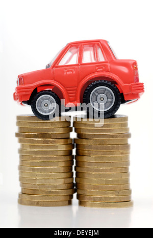 Miniatur-Auto auf einen Stapel von Münzen, Maut symbolisches Bild für Auto Stockfoto