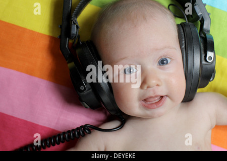 Babymädchen hören hört Musik über Kopfhörer. Baby tragen von Kopfhörern. Stockfoto