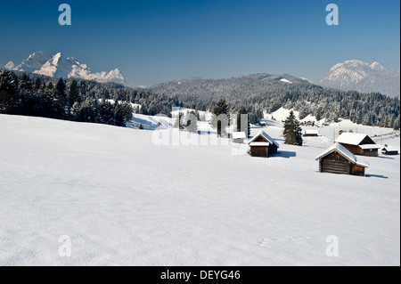 Verschneite Almen und Heustadel, Zugspitze massiv an der Rückseite, Mittenwald, Upper Bavaria, Bavaria, Germany Stockfoto