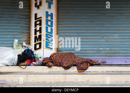 Alte Obdachlose indische Frau Festlegung auf der Straße vor shop Jalousien. Indien Stockfoto