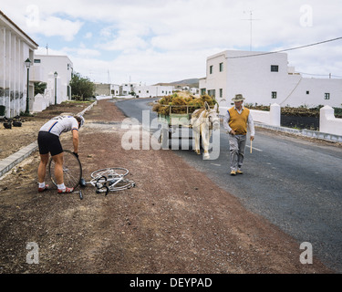 Radfahrer reparieren einen Fahrradreifen Reifenpanne und lokal mit Esel gezogenen Wagen, Straße, Lanzarote Kanarische Inseln Spanien Europa Stockfoto