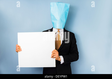 Geschäftsmann mit Papiertüte über den Kopf hält ein leeres weißes Schild Stockfoto
