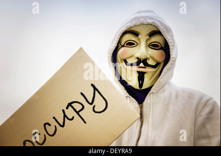 Mann trägt die Guy Fawkes Maske anhand der Occupy-Bewegung mit einem Protest-Schild, protestieren gegen die Macht der Banken Stockfoto