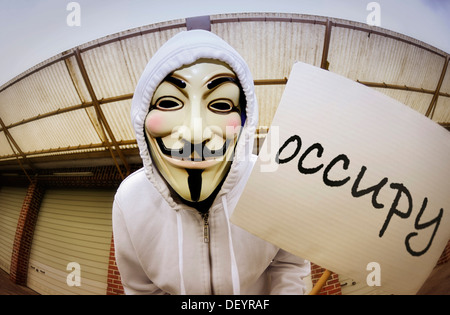 Mann trägt die Guy Fawkes Maske anhand der Occupy-Bewegung mit einem Protest-Schild, protestieren gegen die Macht der Banken Stockfoto