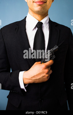 Junger Mann im Anzug ist eine Waffe halten. Stockfoto