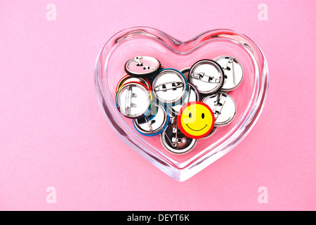 Smiley-Buttons in einer herzförmigen Glasschale Stockfoto