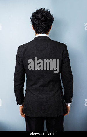 Rückansicht des jungen Multi-rassischen Business-Mann vor einer blauen Wand Stockfoto