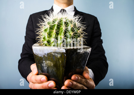 Junger Geschäftsmann mit einem Kaktus Stockfoto