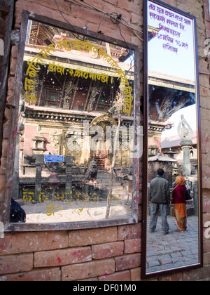 Ein paar steht vor einem Tempel, ihre Reflexion in einem Spiegel, in Changu Narayan, Nepal sichtbar. Stockfoto