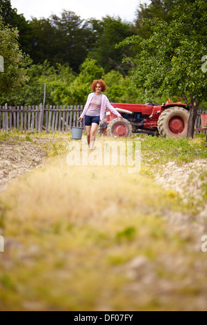 Bauer-Frau, die einen Eimer mit Dünger in einem Obstgarten, mit selektiven Fokus Stockfoto