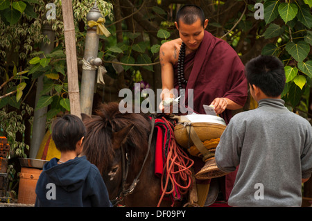 Buddhistischer Mönch zu Pferd mit einer Bettelschale Almosen am Morgen, Tempel und Kloster Wat Phra Archa Thong oder Stockfoto