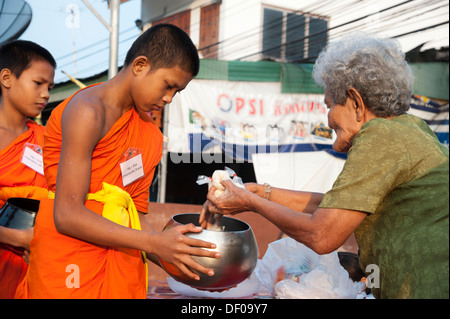 Morgen Almosen rund, junge buddhistischer Mönch aus einer Klosterschule hält eine Bettelschale Essen oder Angebote von erhalten eine Stockfoto