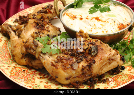 Hausgemachte gebratene Jeera (Kreuzkümmel) Huhn serviert mit Gurken-Raita und Garnierung Koriander Blatt. Stockfoto