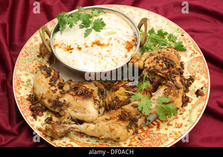 Hausgemachte gebratene Jeera (Kreuzkümmel) Huhn serviert mit Gurken-Raita und Garnierung Koriander Blatt. Stockfoto