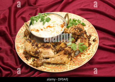 Hausgemachte gebratene Jeera (Kreuzkümmel) Huhn serviert mit Gurken-Raita und Garnierung Koriander Blatt. Stockfoto