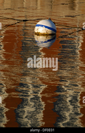 Eine Boje und die Spiegelungen der ein rotes Backsteingebäude im Aal-Teich in Woods Hole in den frühen Morgenstunden, Massachusetts, USA Stockfoto