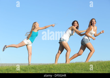 Gruppe von Teenager-Mädchen spielen glücklich werfen Wasser auf dem Rasen mit dem Himmel im Hintergrund Stockfoto