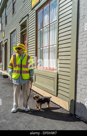 Eine ältere Frau in helles gelb-grün fluoreszierende Warnweste und Hut geht ihr Hund in Waldoboro, Maine. Stockfoto