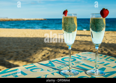 Zwei Gläser Sekt auf den Tisch mit Sandstrand und Meer im Hintergrund Stockfoto