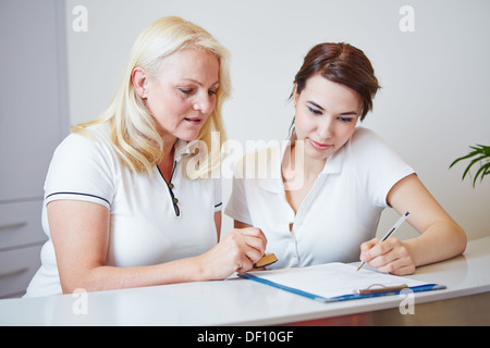 Zwei Ärzte Assistenten, Formular ausfüllen, an der Rezeption mit einem Stift Stockfoto