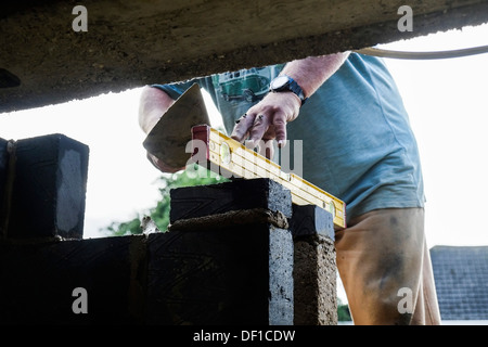 Unter Verwendung eines Niveaus während des Baus einer Mauer Maurer. Stockfoto